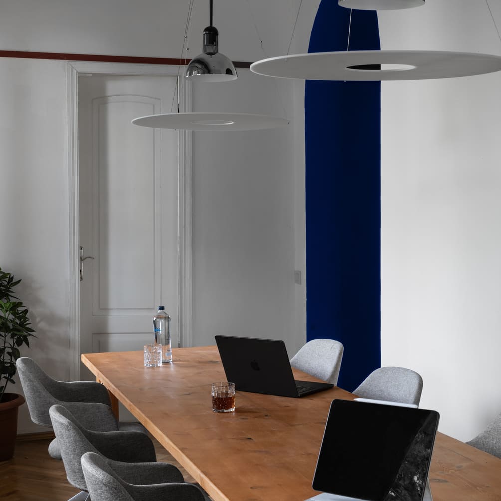 A shared work table at TSRE under a pendant lamp, beside the blue accent wall